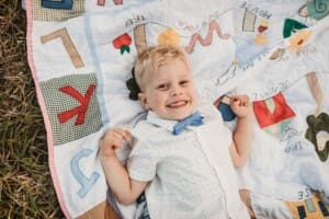 A little boy lays on a bright colourful blanket in the grass