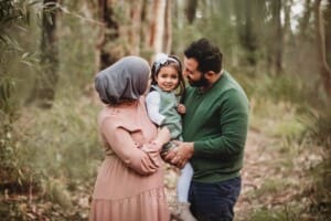 Parents hold their little girl, standing in the bush