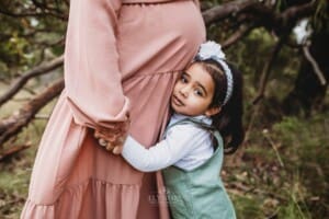 A little girl cuddles her mother's pregnant belly