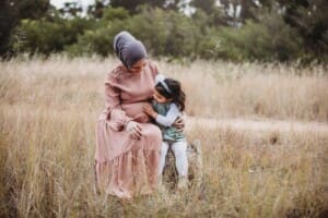 A little girl sits with her hand on her mum's pregnant belly