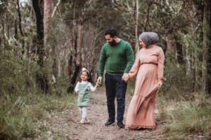 Parents walk their little girl through the trees