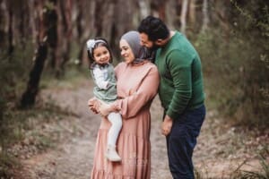 Parents hold their little girl, standing in the bush