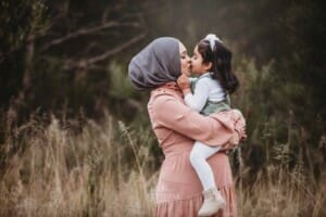 A pregnant mother kisses her little girl