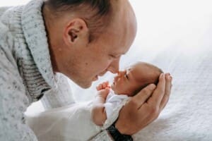 A father presses his nose to his newborn baby girl