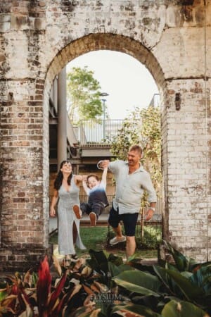 Paddington Gardens, parents hold their son's hands and swing him in the air