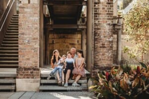 Paddington Gardens, a family sit together laughing on some steps