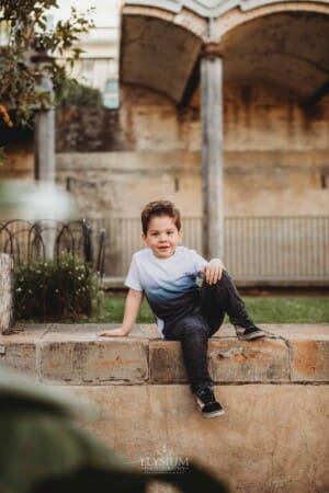 Paddington Gardens, a little boy sits alone on a stone step