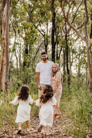2 little girls race towards their parents standing in the bush