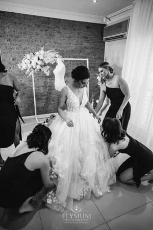 Gledswood Wedding - bridesmaids help the bride into her wedding dress