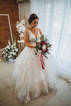 Gledswood Wedding - a bride stands in her gown with her bouquet ready to leave for the ceremony