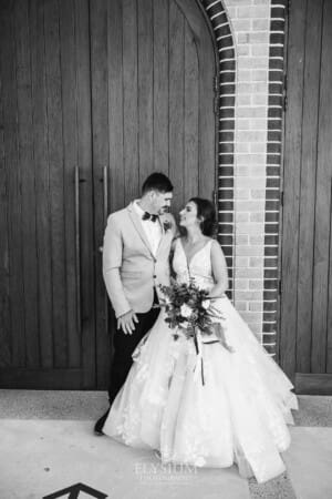 Gledswood Wedding - the newlyweds stand against the churches huge timber doors after the ceremony