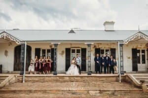 Gledswood Wedding - the bridal party stand on the veranda of the old homestead