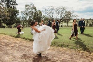 Gledswood Wedding - a groom carries his bride over his shoulder on a dirt driveway at the venue