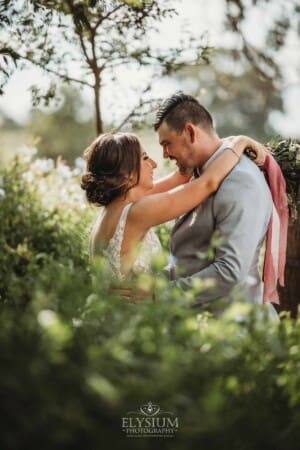 Gledswood Wedding - a bride and groom hug in the gardens at the venue