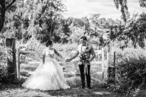 Gledswood Wedding - a bride and groom hold hands in the gardens at the venue
