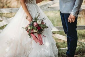 Gledswood Wedding - a bride stands holding her bouquet in the gardens at the venue
