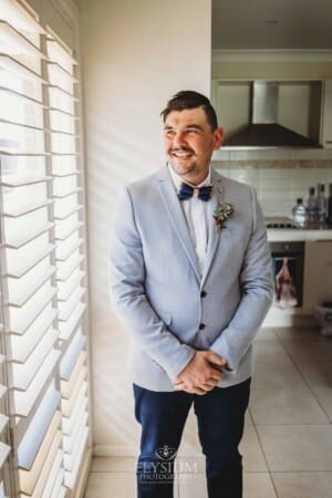 Gledswood Wedding - Groom stands next to a bright window during morning prep