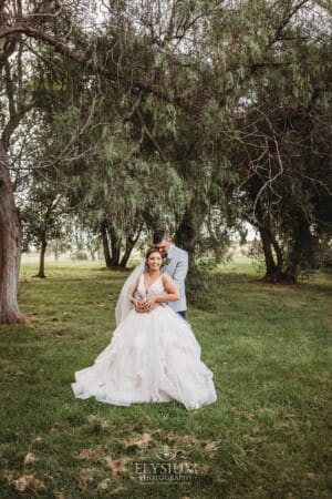 Gledswood Wedding - a bride and groom hug standing in the gardens at the venue