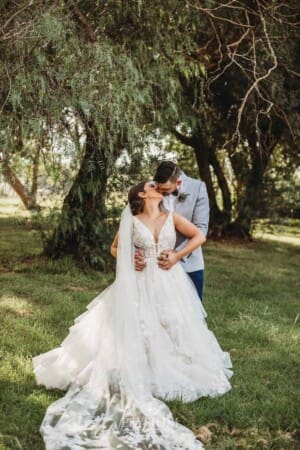 Gledswood Wedding - a bride and groom kiss standing in the gardens at the venue
