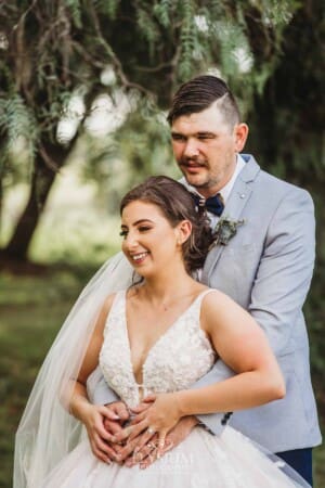 Gledswood Wedding - a bride and groom hug standing in the gardens at the venue