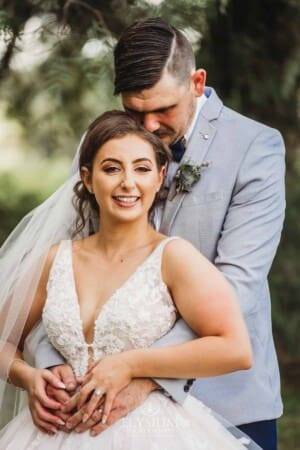 Gledswood Wedding - a bride and groom hug standing in the gardens at the venue