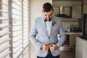 Gledswood Wedding - Groom stands next to a bright window during morning prep