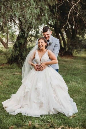 Gledswood Wedding - a bride and groom hug standing in the gardens at the venue