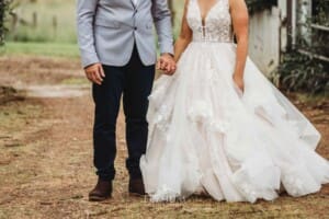 Gledswood Wedding - a bride and groom hold hands standing on a dirt driveway at the venue