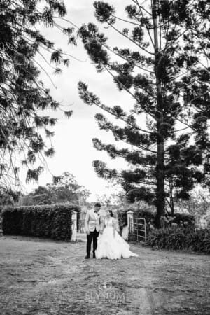 Gledswood Wedding - a bride and groom hold hands standing on a dirt driveway at the venue