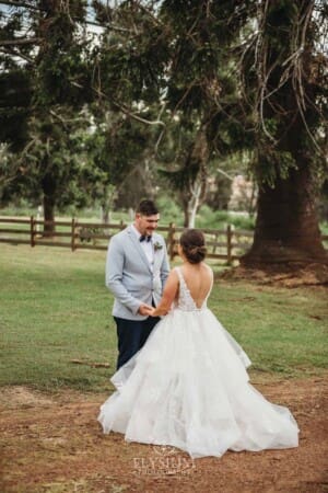 Gledswood Wedding - a bride and groom hold hands standing on a dirt driveway at the venue