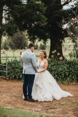 Gledswood Wedding - a bride and groom hold hands standing on a dirt driveway at the venue