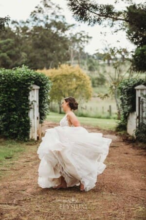 Gledswood Wedding - a bride twirls her dress while standing on a dirt driveway at the venue