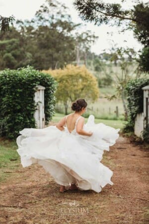 Gledswood Wedding - a bride twirls her dress while standing on a dirt driveway at the venue