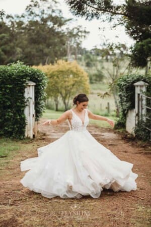 Gledswood Wedding - a bride twirls her dress while standing on a dirt driveway at the venue