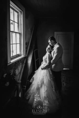 Gledswood Wedding - a bride and groom stand in a rustic room at their reception venue