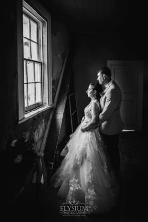 Gledswood Wedding - a bride and groom stand in a rustic room at their reception venue