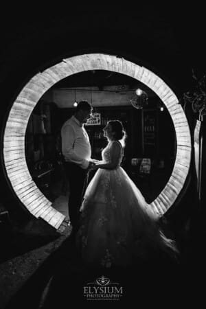 Gledswood Wedding - Newlyweds stand in a circular doorway with a bright light behind them