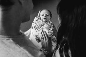 A newborn baby held in her parents arms