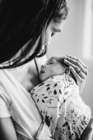 A mother holds her baby girl to her chest and strokes her head