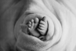 Newborn baby toes wrapped in a soft white blanket