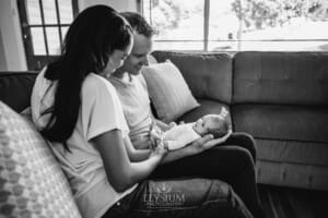 A newborn baby held in her parents arms