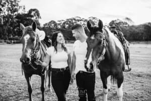 An engaged couple walk with their horses at sunset