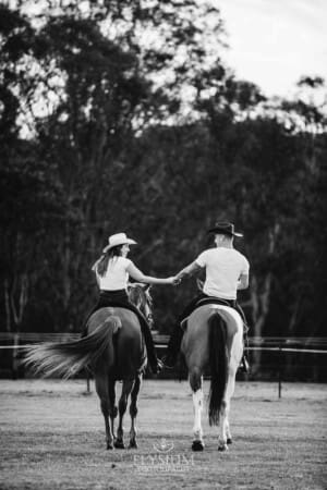 An engaged couple walk with their horses at sunset