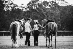 An engaged couple walk with their horses at sunset