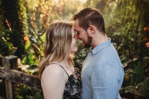 A couple stand on a boardwalk with their foreheads pressed together