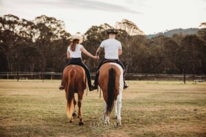 An engaged couple walk with their horses at sunset