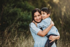Family Session - A mother hugs her son at sunset in a grassy field