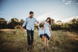 Family Session - parents hold their son's hands and swing him as they walk