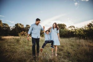 Family Session - parents hold their son's hands and swing him as they walk