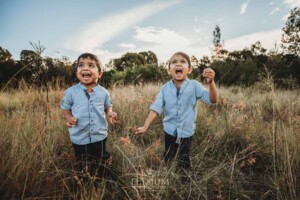 Family Session - little boys stand in long grass at sunset and giggle